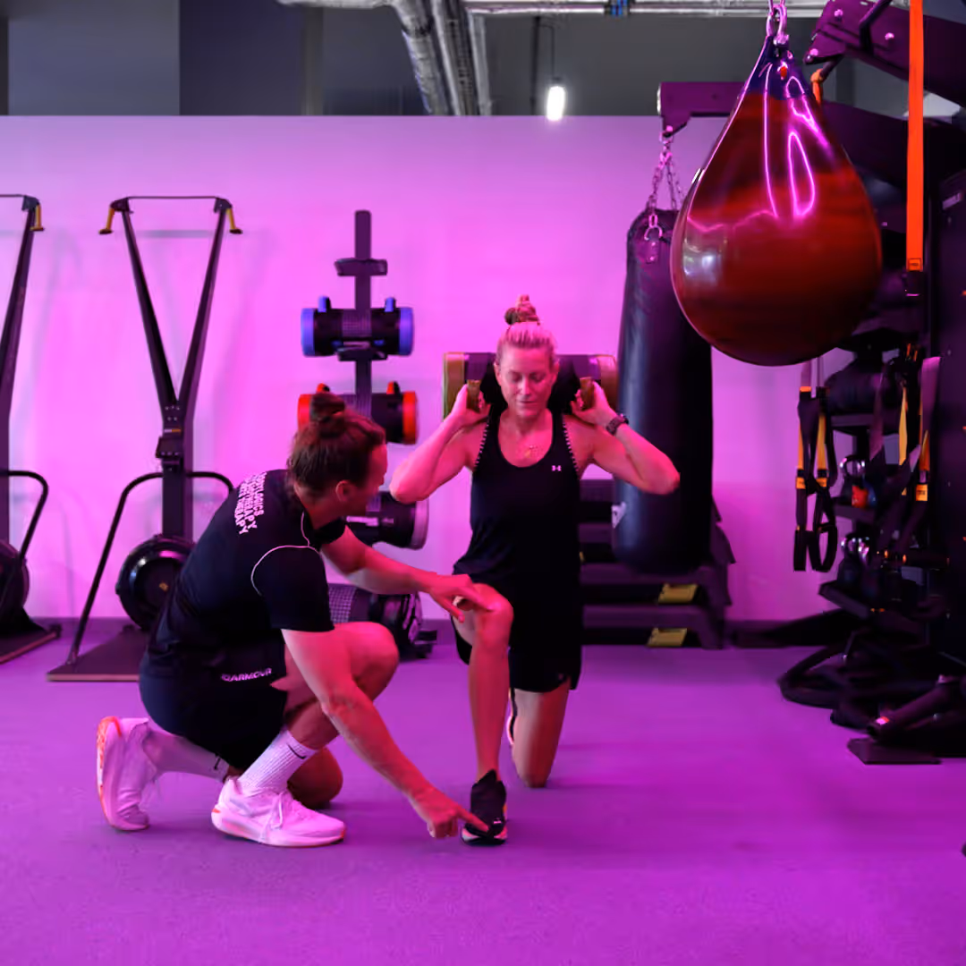 A Bodylogics trainer coaching a client through a lunge in the gym